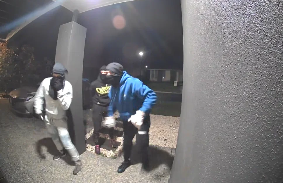 Hooded person reaching towards a home security camera